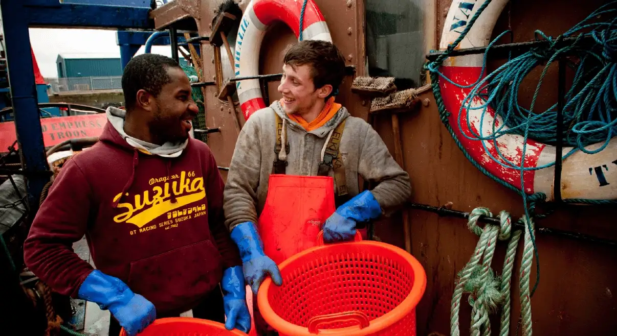 Two seafarers on the deck of ship working hard.
